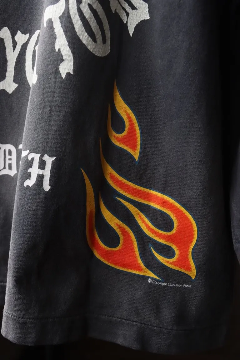 SAINT Mxxxxxx M/AFTER LS_TEE/BLACK Flame arrow Letter M retro distressed long tee Washed black S-XL Tubular fabric Assute ready-made garments dyed The whole piece is sprayed with horse-hair spray and then sprayed again to fade the color. The collar and cuffs are frayed. Many places are frayed. Extra large printing position. Very difficult to print. Complete accessories. With little angel anti-counterfeiting label.